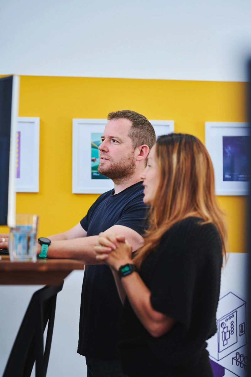 Kevin Triggle and Laura Pinkstone speaking at Kevin's desk